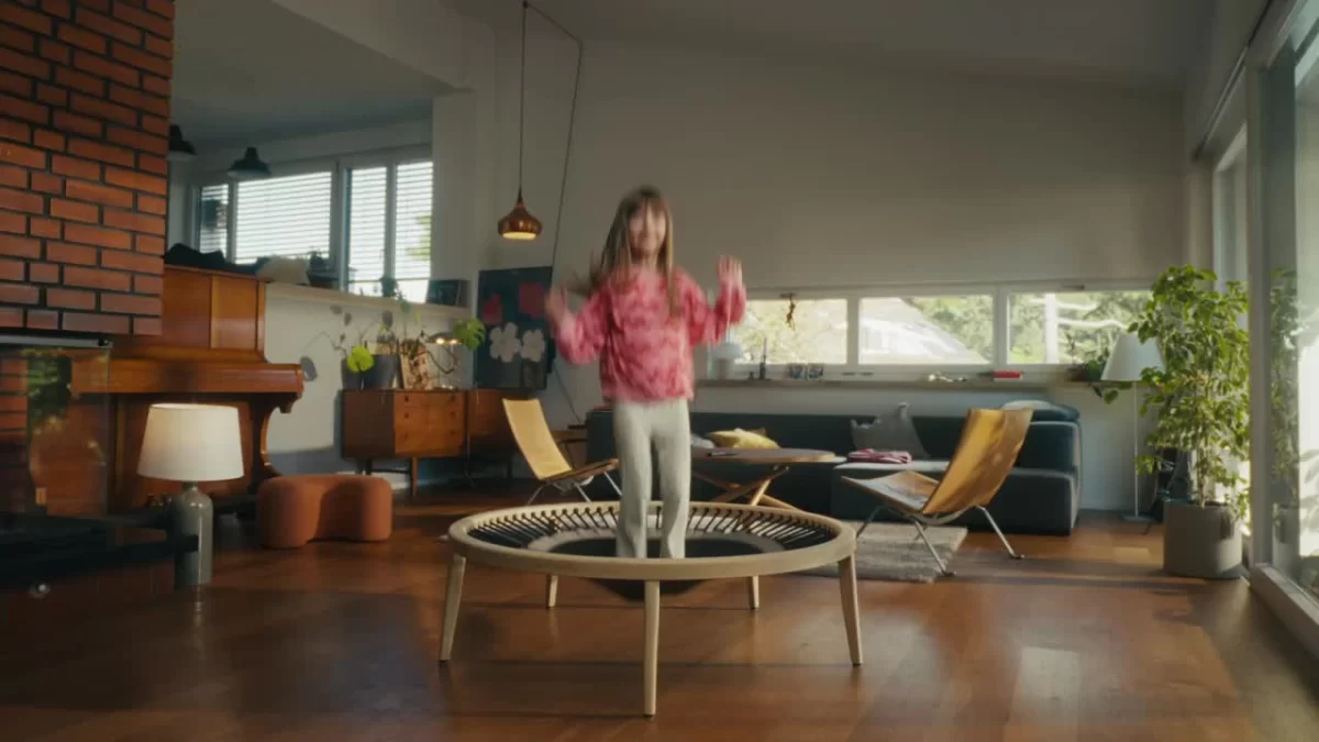 Frau springt auf einem Holztrampolin in einem Wohnzimmer