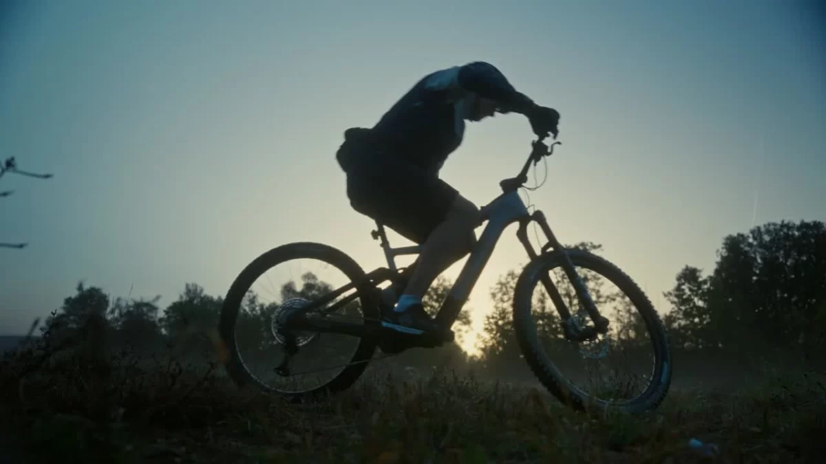 Mountainbiker fährt im Gegenlicht über einen Hügel